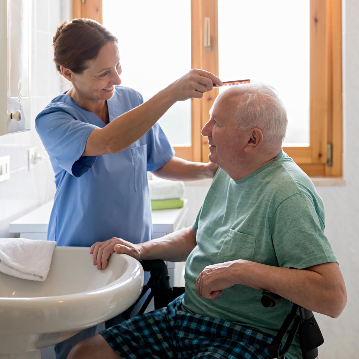 Caregiver combing an elderly man's hair